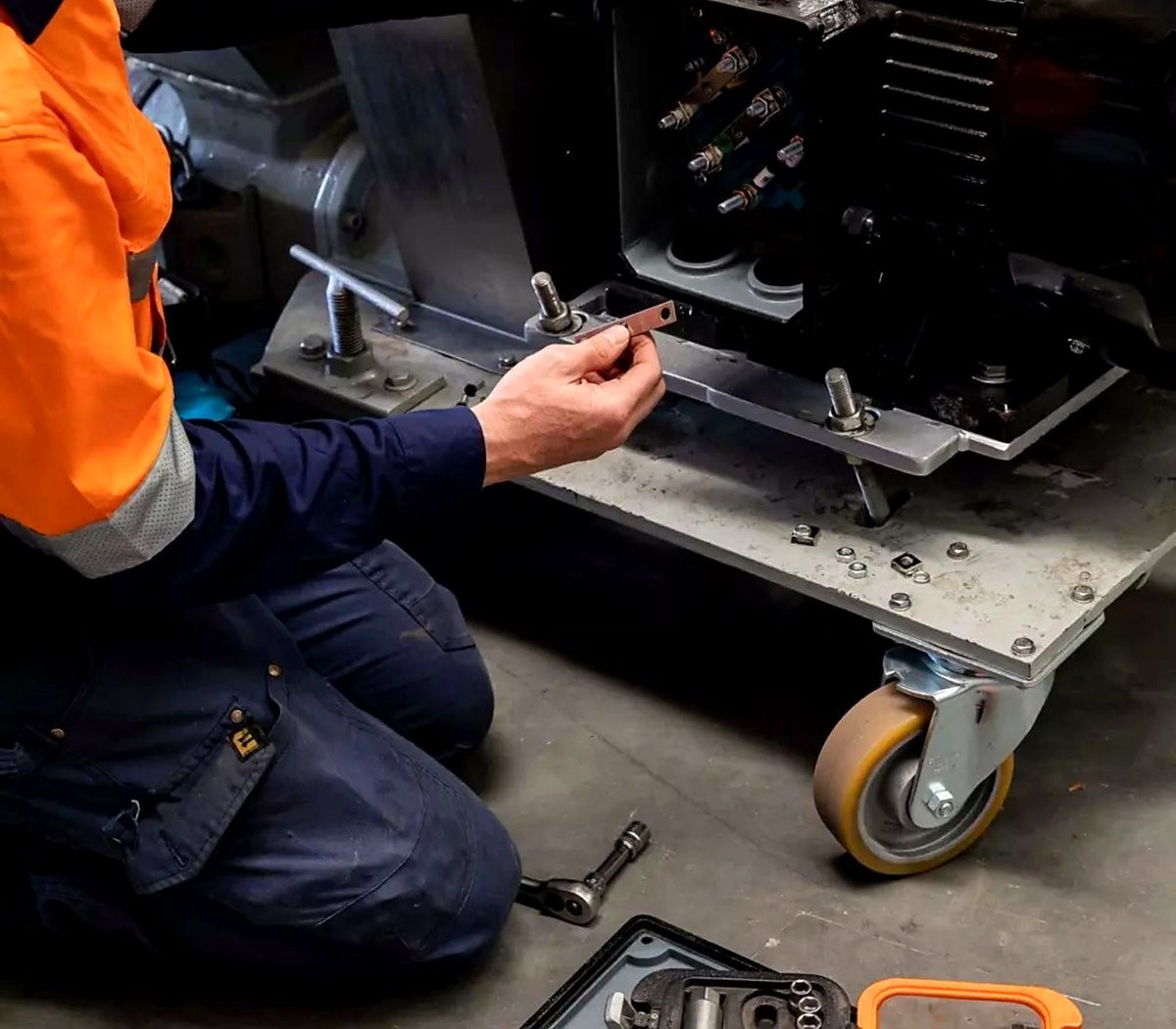 Técnico agachado reparando componentes elétricos de um equipamento